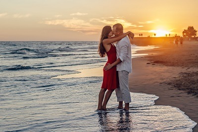 middle-age man and woman hugging and kissing at a beach in sunset